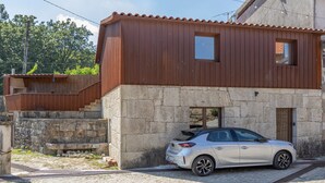 Un edificio a due piani con facciata in pietra e sezione superiore in legno. Un'auto è parcheggiata davanti.