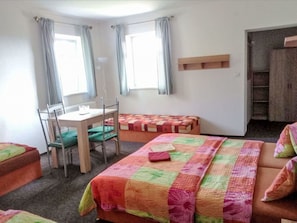 Une pièce comprenant un lit, un bureau et une chaise. Il y a deux fenêtres avec des rideaux.