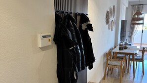 Een hal met een kapstok, een bank en een eethoek met een tafel en stoelen.