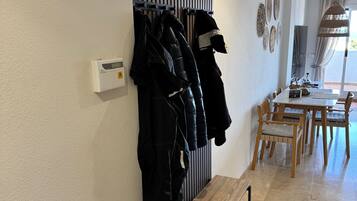 A hallway with a coat rack, a bench, and a dining area with a table and chairs.