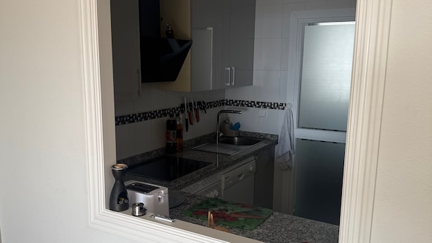 Een keuken met een fornuis, spoelbak en kasten.