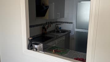 A kitchen with a stove, sink, and cabinets.