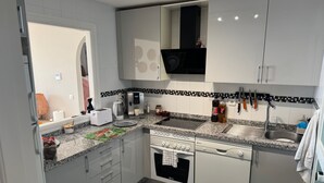 Een moderne keuken met een inbouwoven, een koffiezetapparaat en een spoelbak.