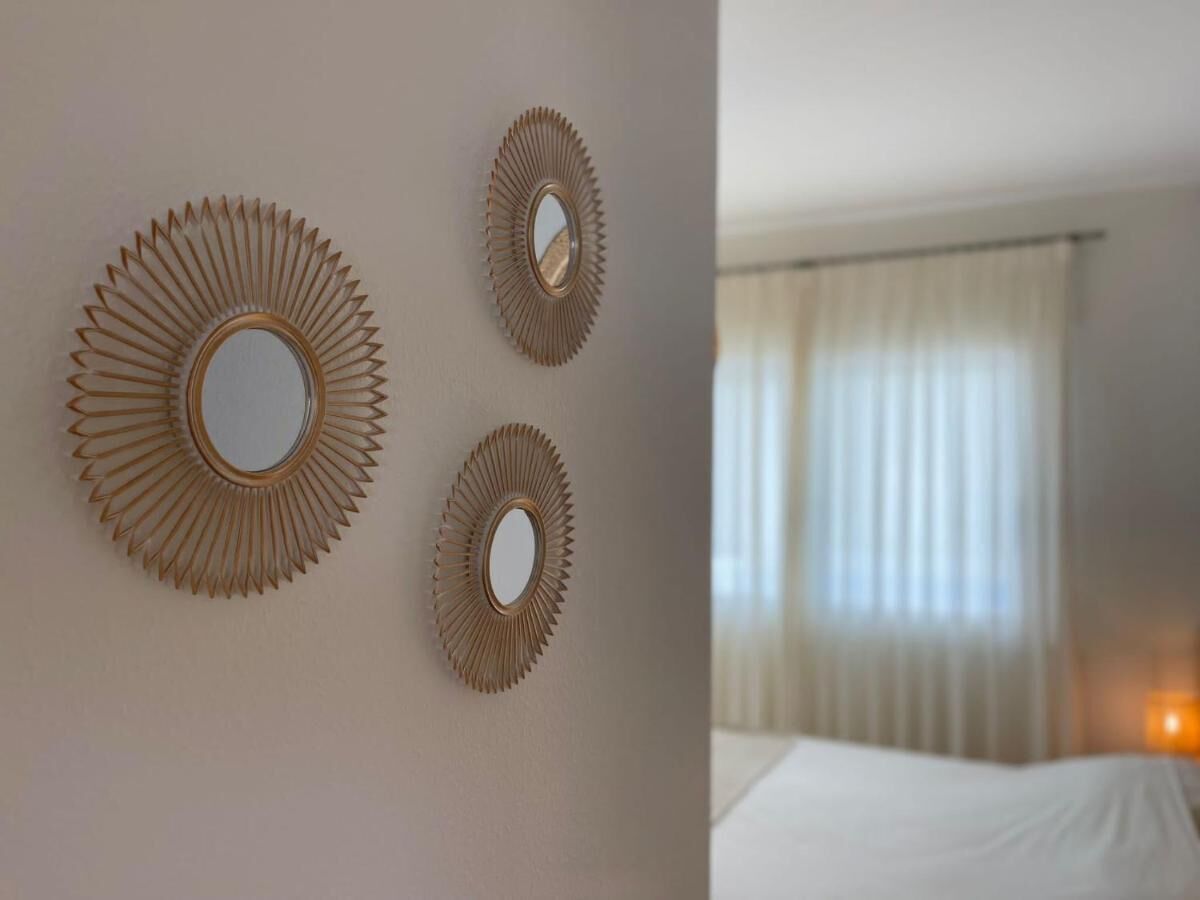 A hotel room with a large bed, a wall-mounted mirror, and a window with curtains.