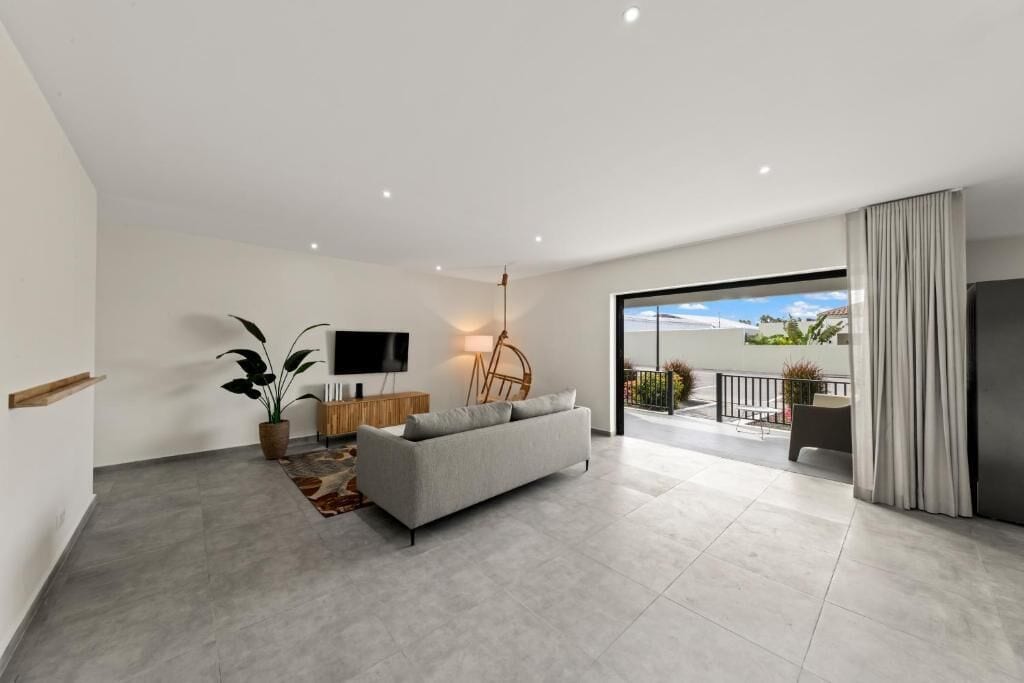 A modern living room with a sofa, TV, and a large window.