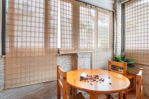 A room with a round wooden table, two chairs, and a woven bamboo screen.