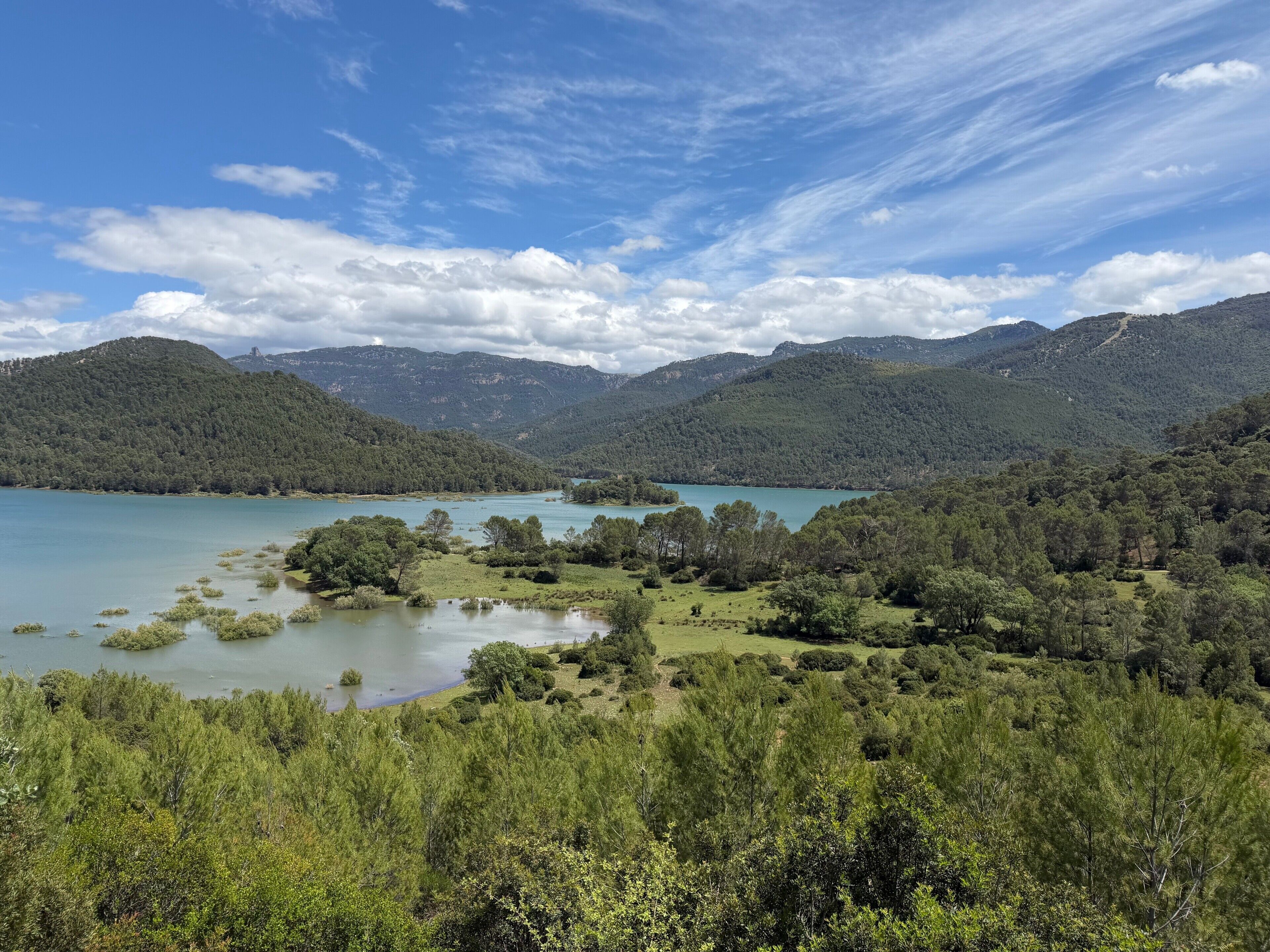 Eine Berglandschaft mit einem See, üppigem Grün und wolkenlosem Himmel.
