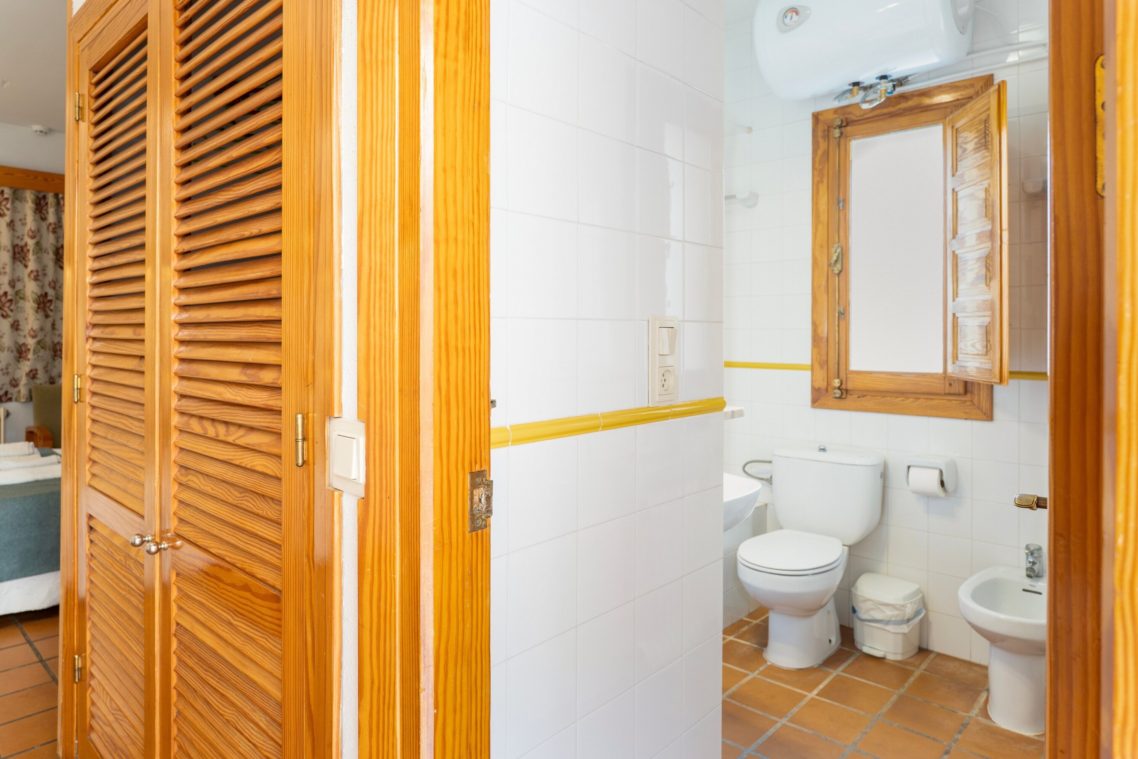 Un bany amb vàter, bidé i un mirall sobre el lavabo.