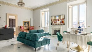En rummelig stue med en stor sofa, et spisebord til fire og en pejs.
