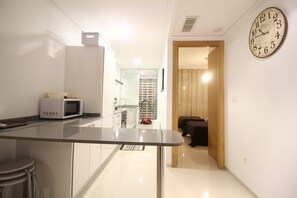 A modern kitchen with a microwave, a glass-top table, and a view into a bedroom. - Varudi1.09 (Torrevieja)