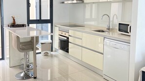 A modern kitchen with a central island, stainless steel appliances, and a dishwasher. - Duplez Zenia Beach (Orihuela)