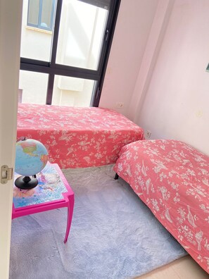 A small room with two beds, a globe on a table, and a window.