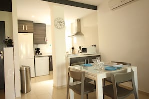 A modern kitchen with a dining area, featuring a microwave, stove, sink, and a clock on the wall. - Ground Floor Oasis Beach IV (Orihuela)
