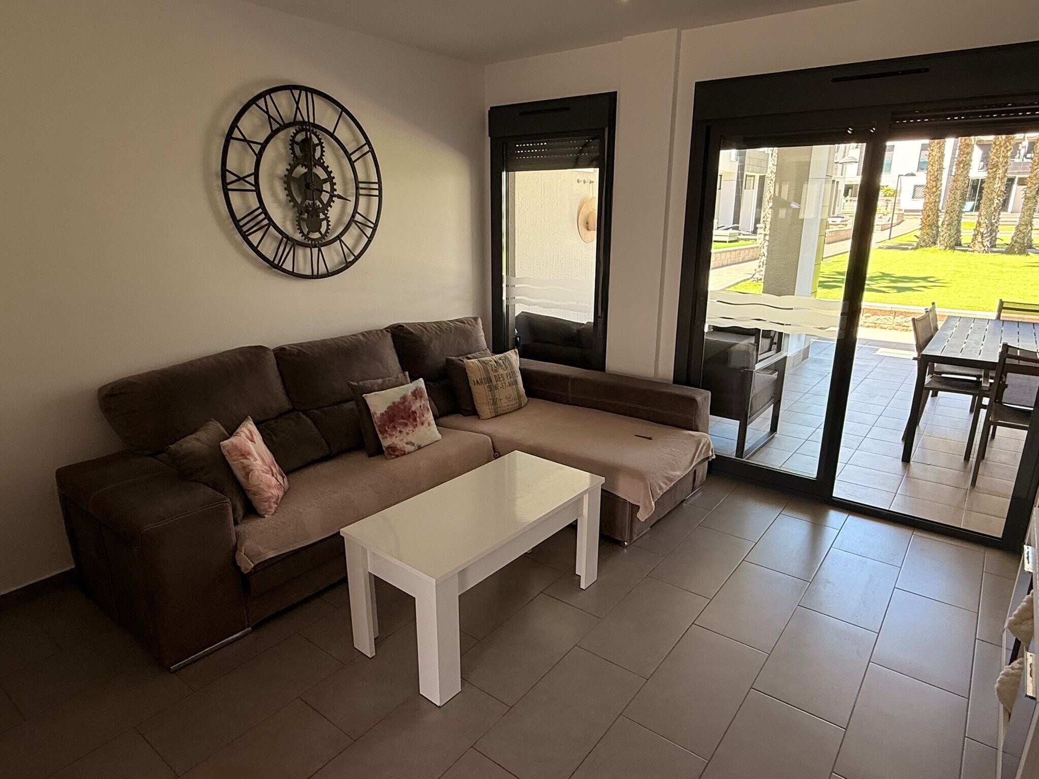 A modern living room with a sofa, coffee table, and a large wall clock.