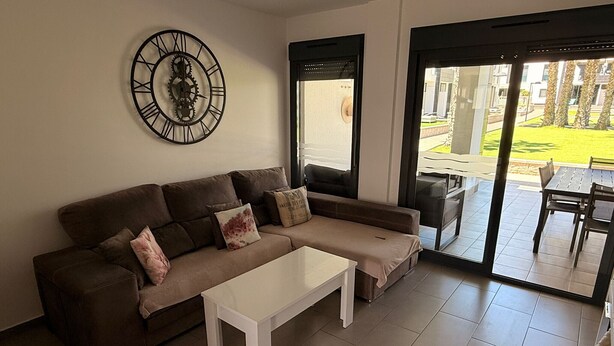 Uma sala de estar moderna com um sofá, mesa de centro e um relógio de parede grande.