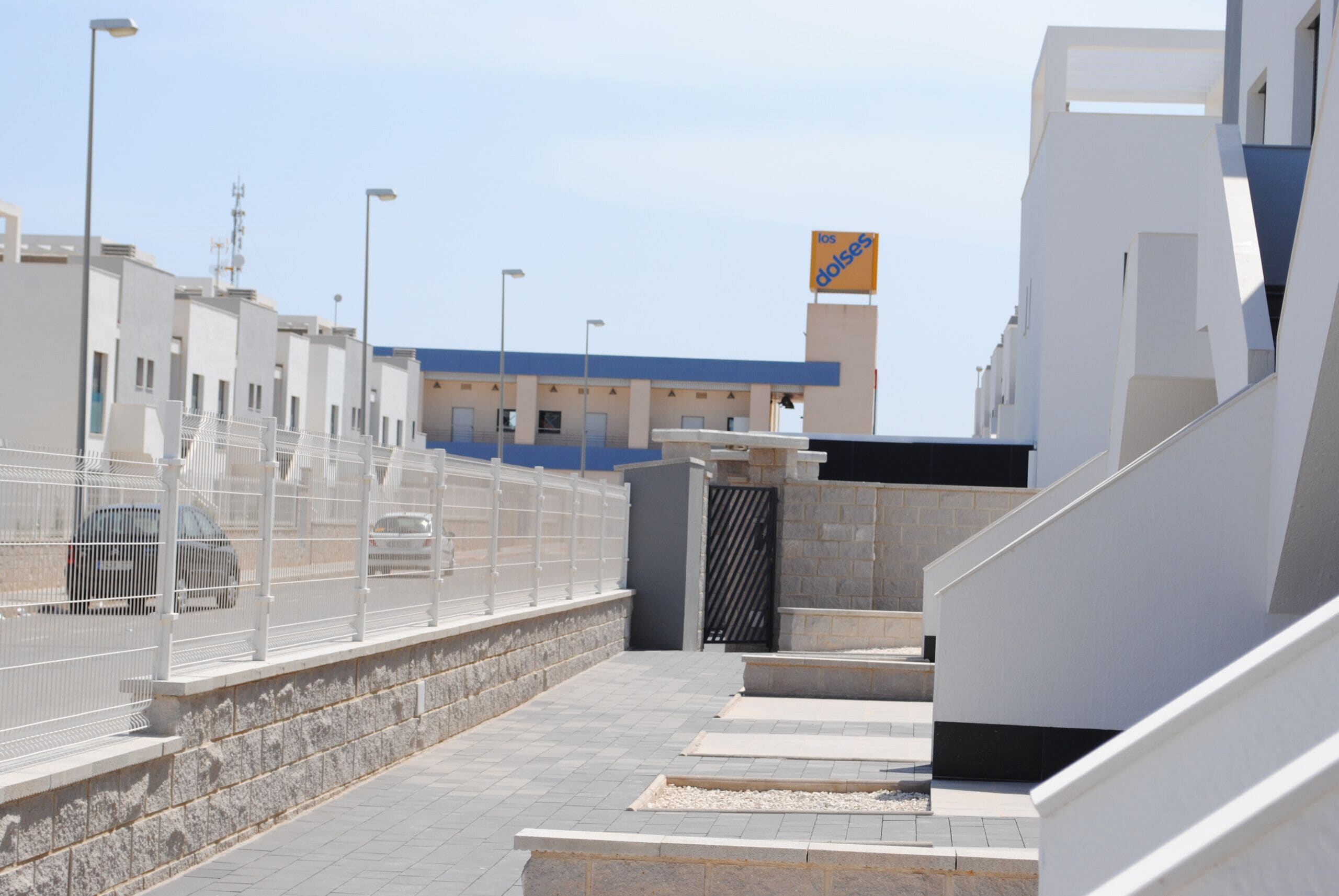 Un bâtiment moderne avec un toit bleu, une clôture blanche et une enseigne portant l’inscription « los doloses ».