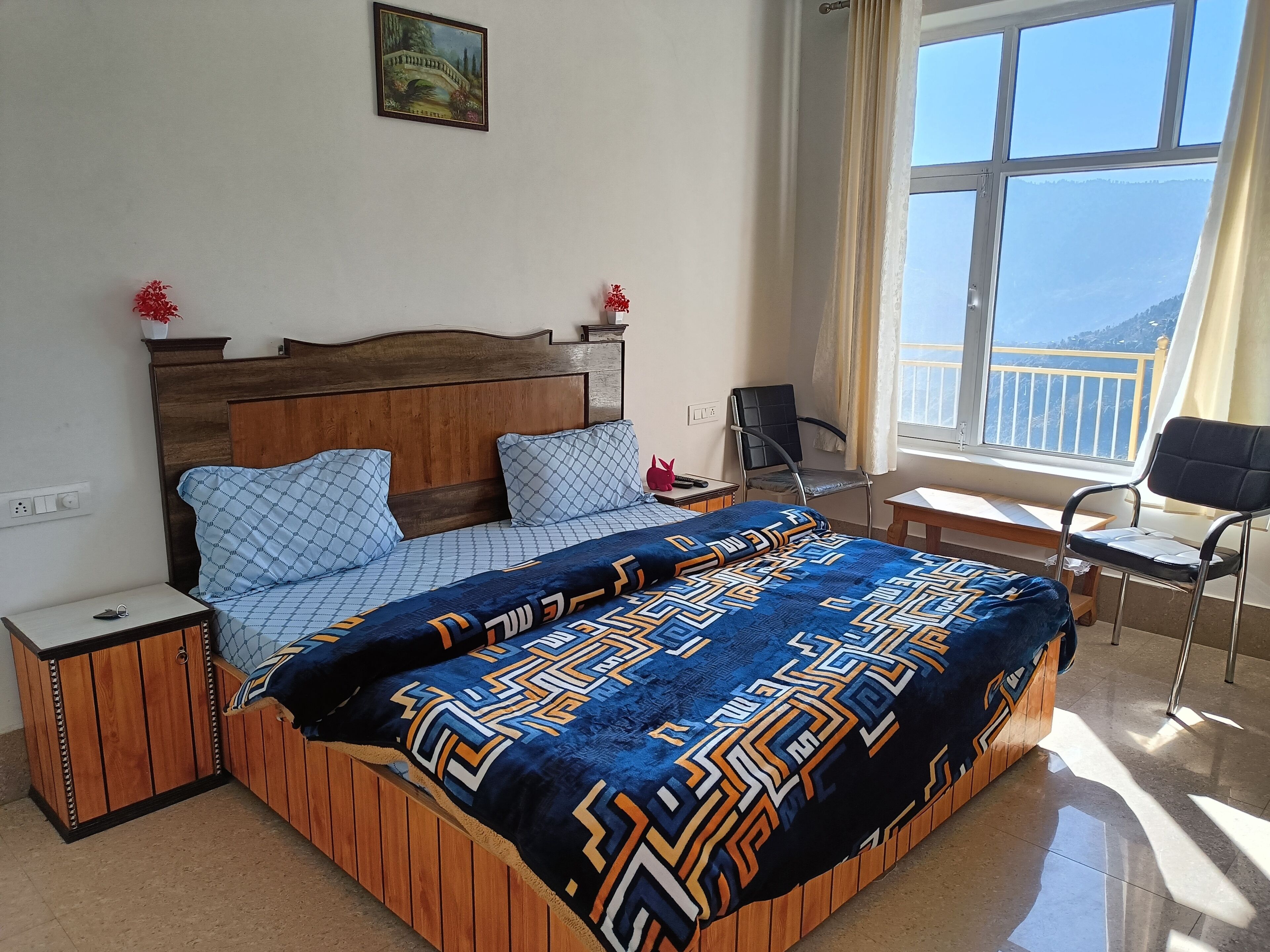 Un dormitorio ordenado con cama, mesitas de noche, una silla y ventana con vistas.
