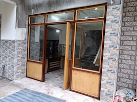 A room with a wooden door leading to a staircase, tiled walls, and a marble floor.