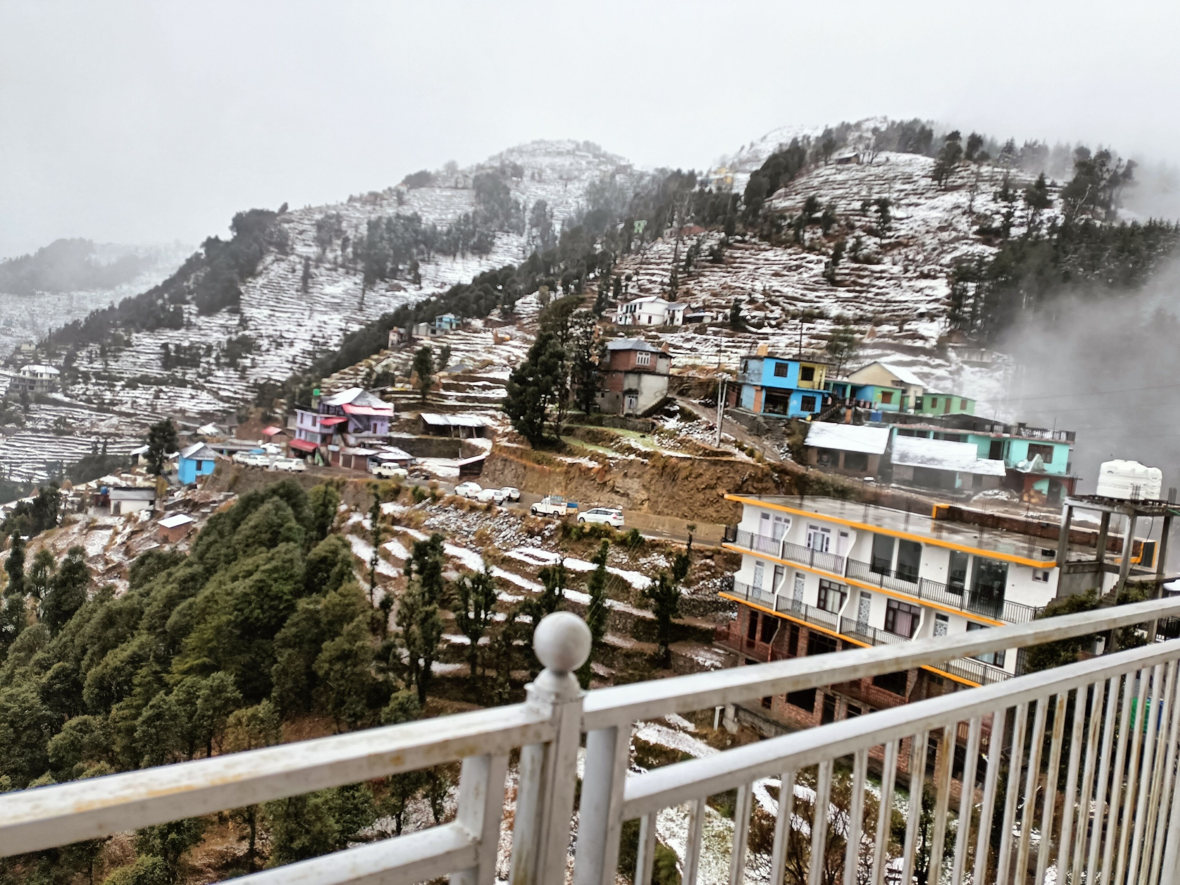 A mountainous landscape with terraced fields, buildings, and a clear view of the valley below.