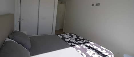 A bedroom with a bed, a wardrobe, and a chair.