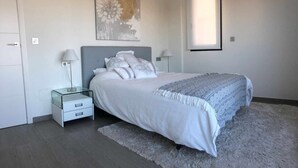 A bedroom with a bed, nightstands, a rug, and a painting on the wall. - House Tindra Homes Punta Prima (Torrevieja)