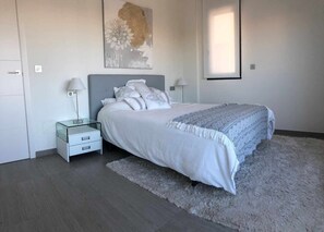 Ein Schlafzimmer mit einem Bett, Nachttischen, einem Teppich und einem Bild an der Wand.