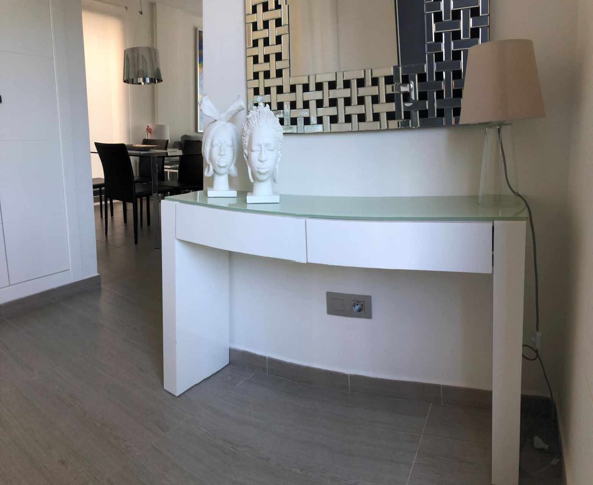 A modern kitchen with a curved white countertop, a built-in microwave, and a small electrical outlet.