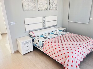 A bedroom with a bed, a nightstand, a drawer unit, and wall art. - House Tindra Homes Punta Prima (Torrevieja)