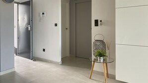 A modern hallway with a glass table, a clock, and a door with a keypad lock. - Groundfloor Oasis Beach Punta Prima IX (Torrevieja)