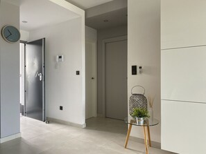 A modern hallway with a glass table, a clock, and a door with a keypad lock. - Groundfloor Oasis Beach Punta Prima IX (Torrevieja)