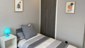 A bedroom with a bed, a nightstand, a lamp, and two framed artworks on the wall. - Groundfloor Oasis Beach Punta Prima IX (Torrevieja)