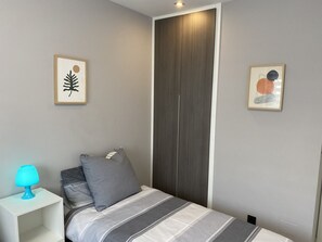 A bedroom with a bed, a nightstand, a lamp, and two framed artworks on the wall. - Groundfloor Oasis Beach Punta Prima IX (Torrevieja)
