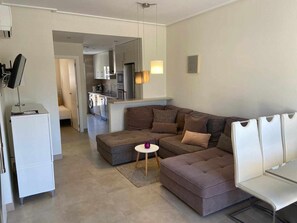 A modern living room with a sectional sofa, a small round table, and a white cabinet.