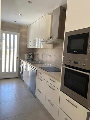 A modern kitchen with stainless steel appliances, white cabinetry, and a built-in dishwasher.