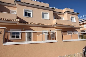 Ein mehrstöckiges Gebäude mit Balkonen, weißen Geländern und einer beige farbenen Fassade.