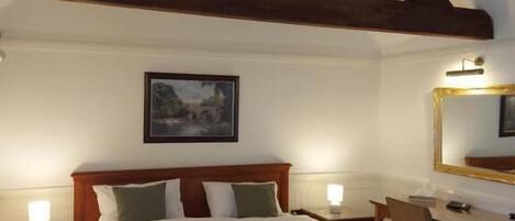 Un dormitorio con una cama grande, vigas de madera, un escritorio y una silla.
