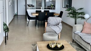 Ein modernes Wohnzimmer mit Couch, grauem Sessel und Couchtisch aus Holz.