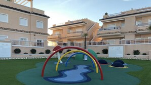 Ein Spielplatz mit einer Kletterkonstruktion in Regenbogenfarben und einem gewundenen Weg.