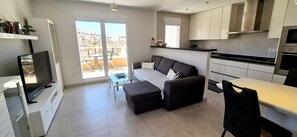 Eine moderne Küche mit Essbereich, einer Couch und einem Fernseher.