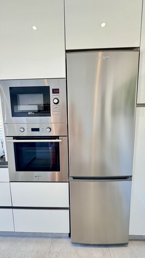 A stainless steel kitchen with a built-in oven, microwave, and refrigerator. - Penthouse Punta Prima Vistazul (Torrevieja)