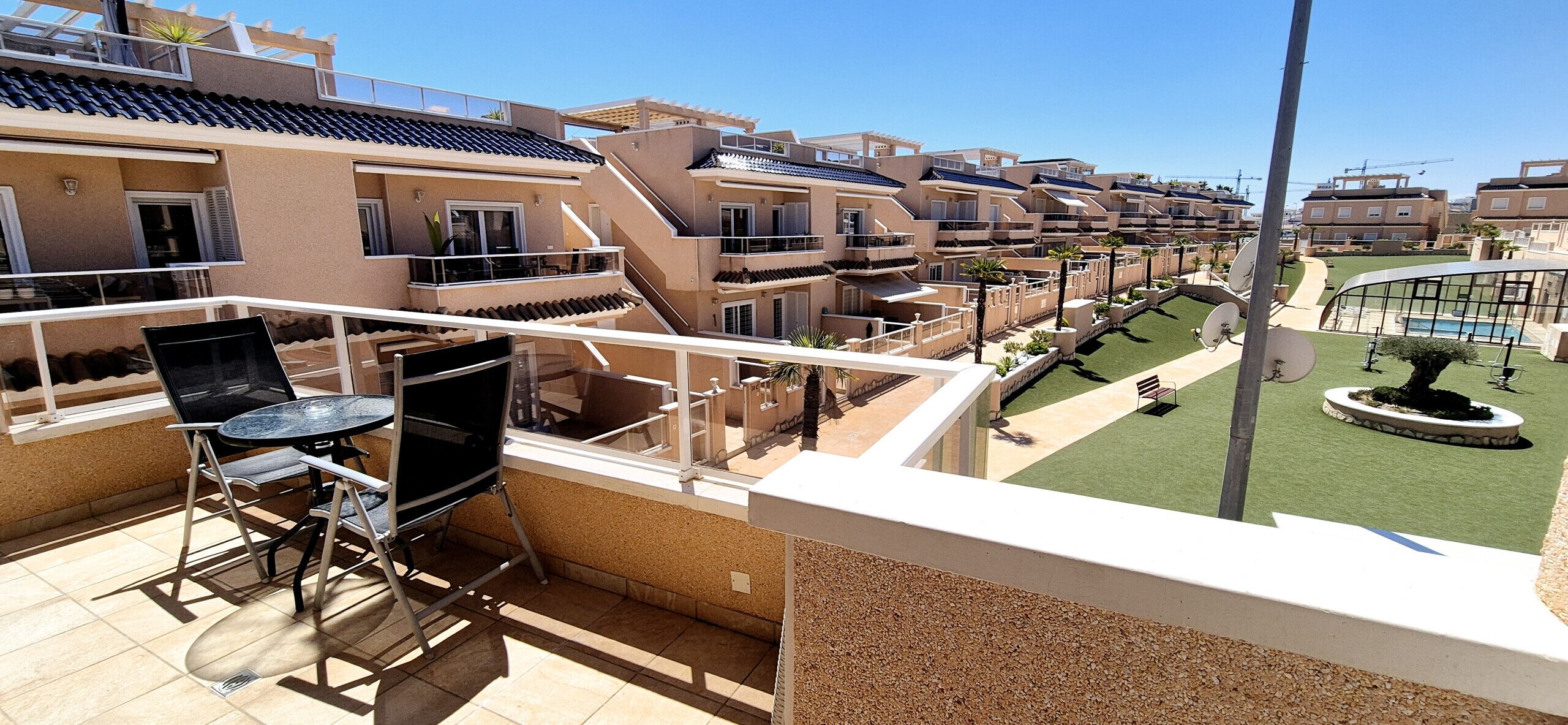 A residential building with multiple balconies, a pool, and a well-maintained lawn.