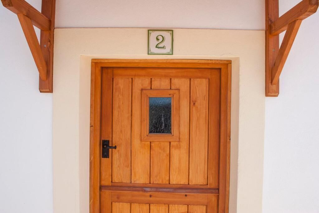 A wooden door with a small window, a number '2' sign above it, and a simple latch.