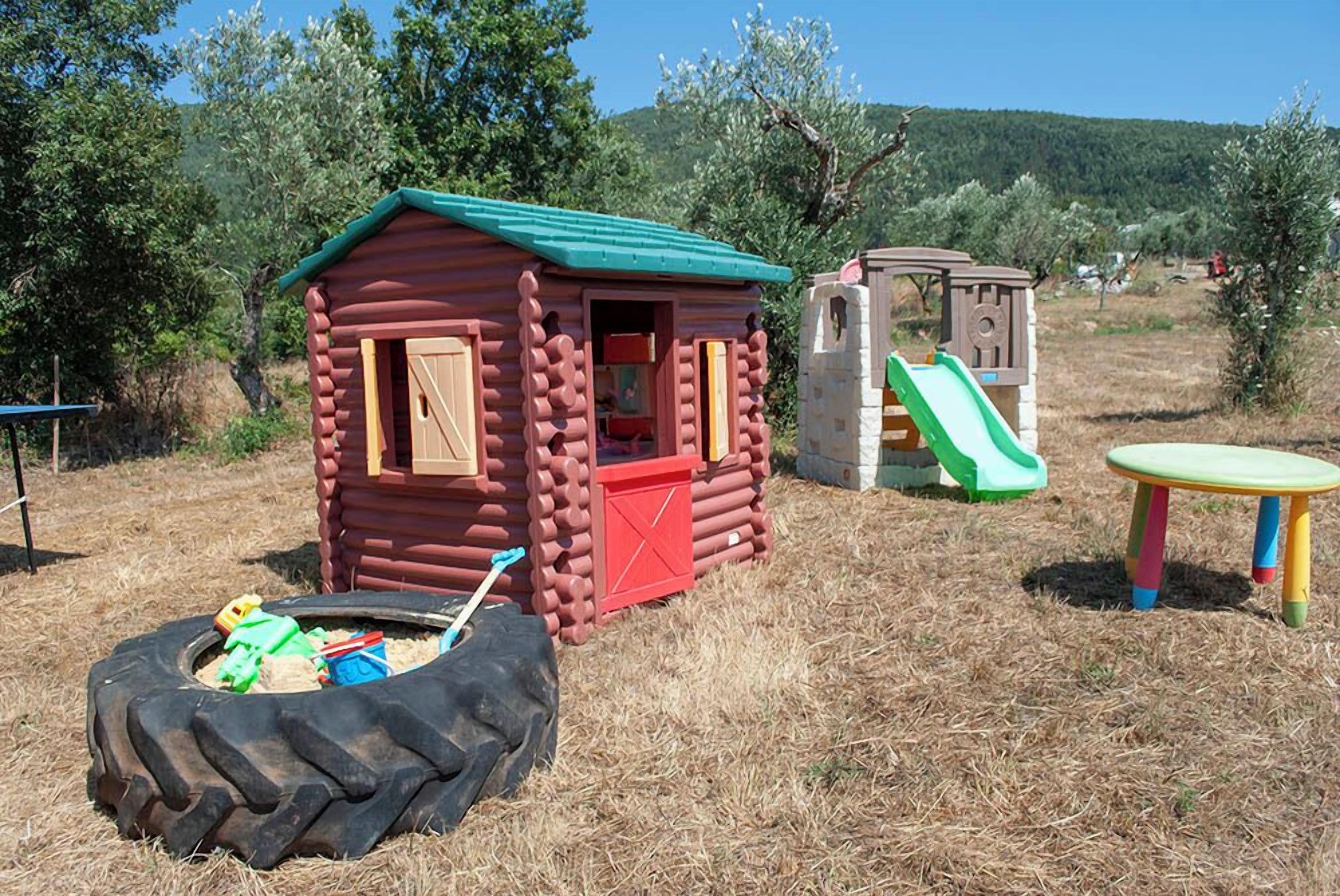A children's play area with a log cabin, a slide, and a tire swing.