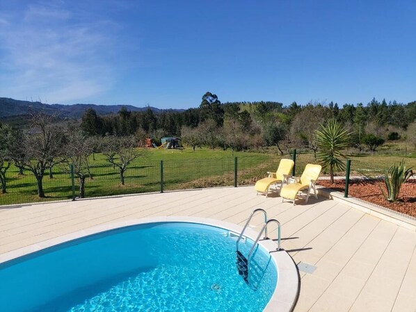 A swimming pool with a clear view of the surrounding landscape, including trees and a distant mountain range.