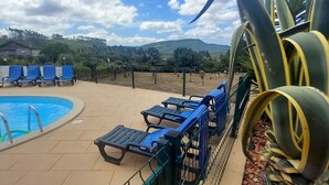 A pool area with blue lounge chairs and a fenced pool. - Casa De Campo De Oliveiras (Penela)