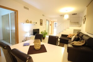 Ein modernes Wohnzimmer mit Esstisch, schwarzer Ledersofa und einer Treppe.