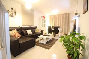 A modern living room with a black sofa, white coffee table, and a potted plant. - Penthouse Aguas Nuevas Varudi Complex (Torrevieja)