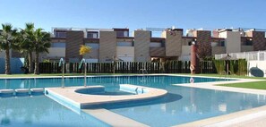 A swimming pool with a circular section, surrounded by a fence and palm trees. - Penthouse Aguas Nuevas Varudi Complex (Torrevieja)