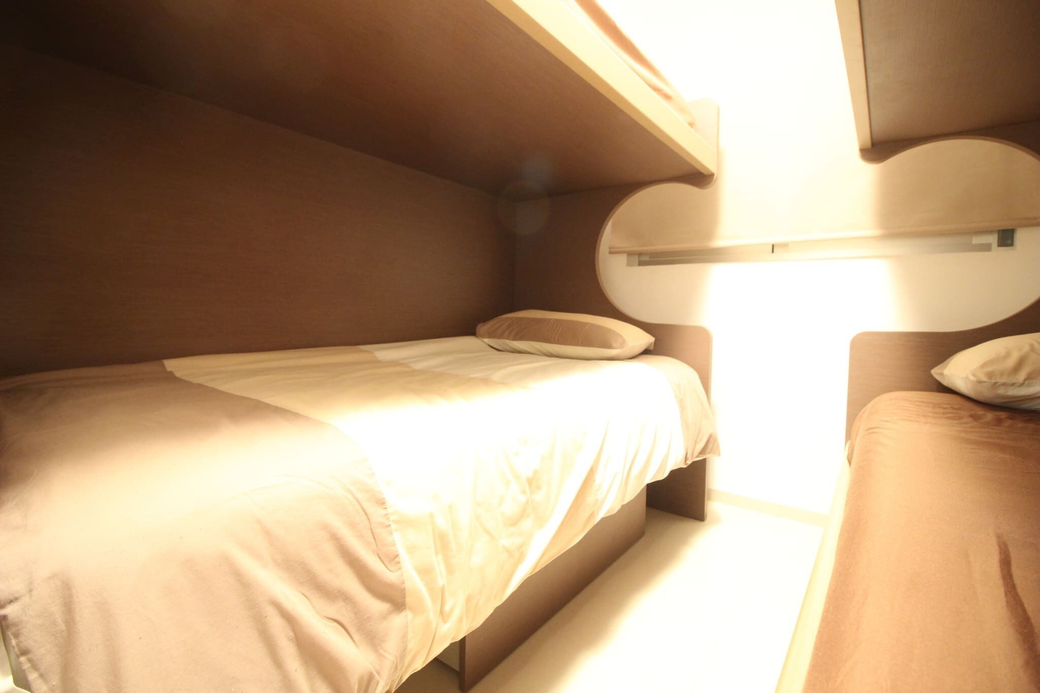 A small, compact room with a bunk bed and a single bed, both with plain bedding.