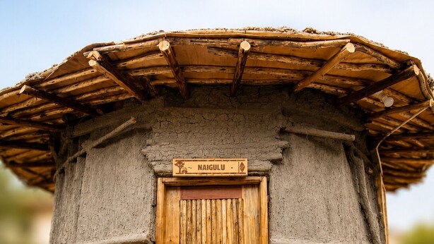 Una estructura cilíndrica con una puerta de madera y un letrero encima.